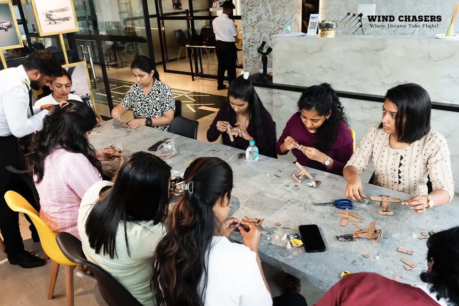 Attendees assembling wooden model aircraft around a long table