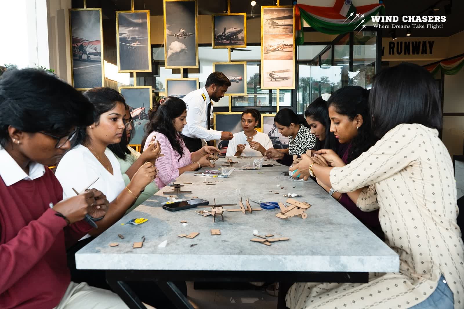 Attendees building model aircraft in a room lined with framed aircraft photographs